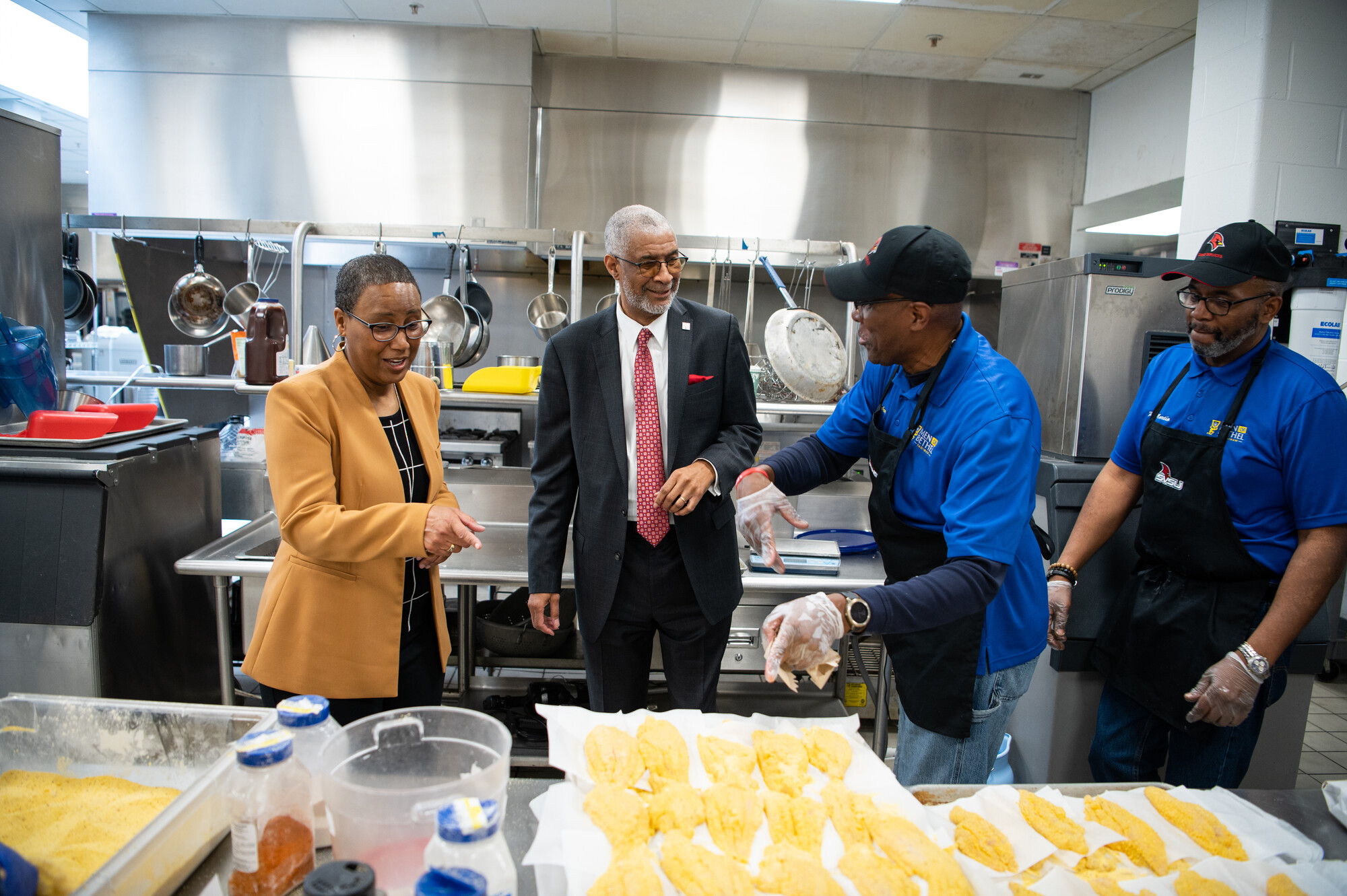 Cooks and SVSU President talking over prepared food